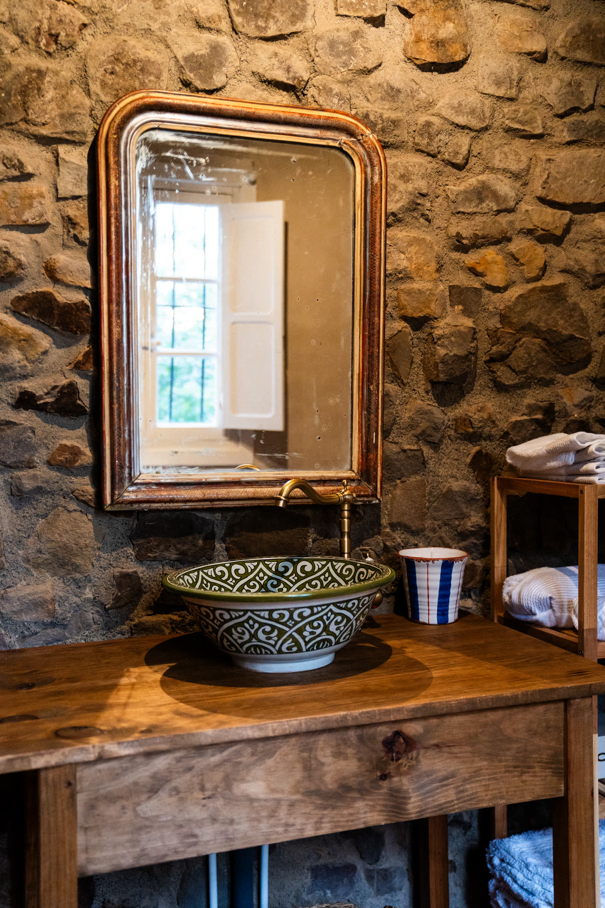 Baño con muro de piedra y lavabo cerámico artesanal