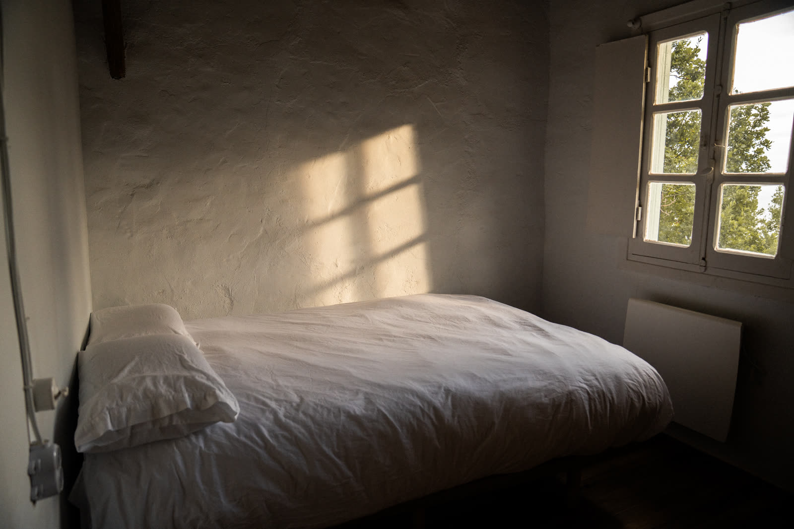 Sombras cálidas sobre muros a la cal en habitación doble
