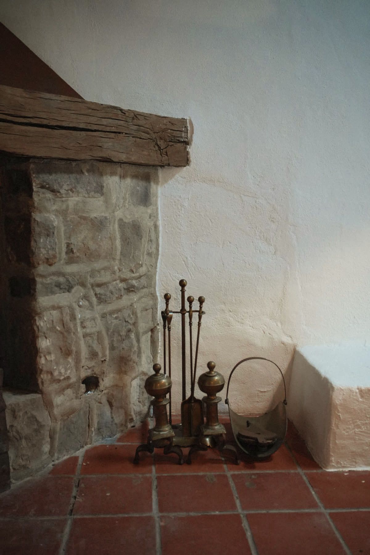 Chimenea tradicional de piedra y morillos de latón
