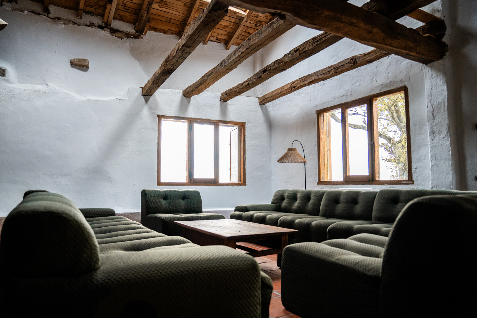 Salón principal de Sanjoanalde con sofá verde musgo y vigas de roble
